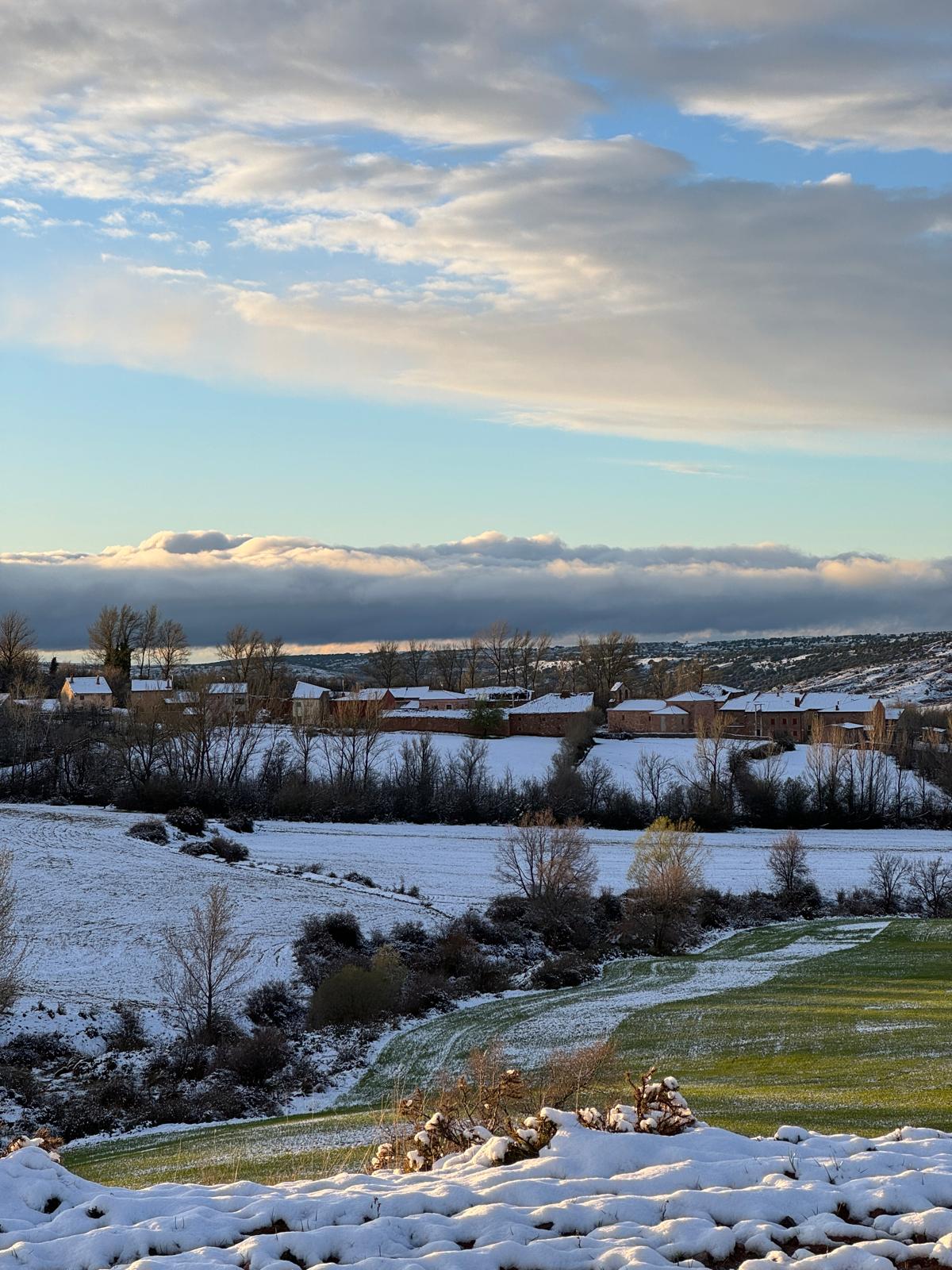 Rebollosa de Pedro cubierto de nieve al atardecer, con un banco de nubes sobre el valle del río Pedro